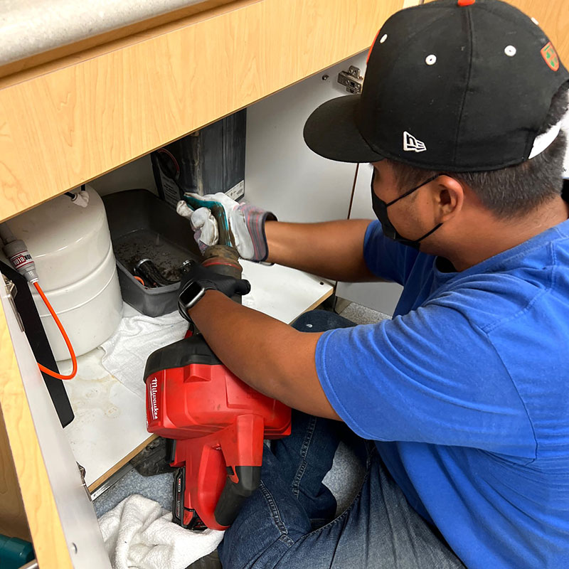 image of Waialae plumbing tech clearing a clogged drain in a house.